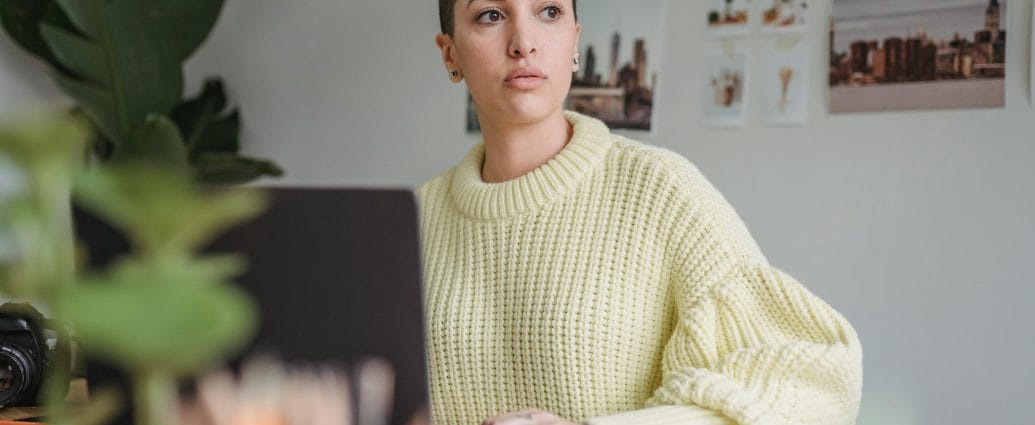 Woman reflecting on her career, work, and income while working on a laptop