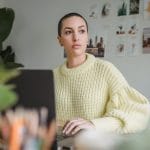 Woman reflecting on her career, work, and income while working on a laptop