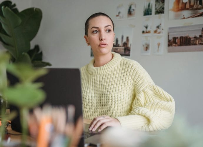 Woman reflecting on her career, work, and income while working on a laptop