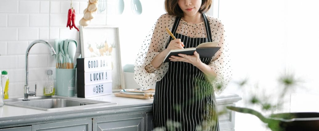 Woman analyzing eating habits after 40 with a notebook and simple healthy food on a calm kitchen table.