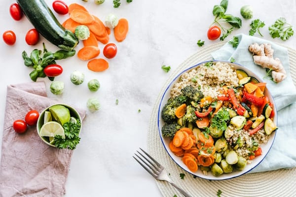 Colorful healthy meal with quinoa, vegetables, and fresh herbs on a white table