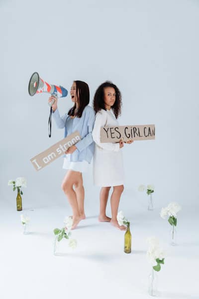 Two confident women holding empowering signs that say "I am strong" and "Yes, girl can" — symbolizing the power of steady progress and self-belief through one change at a time