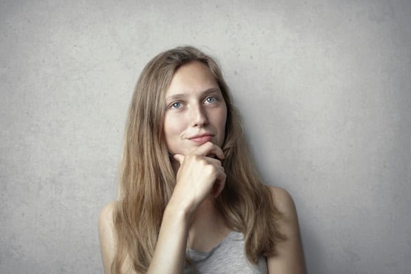 Confident young woman reflecting with a hand on her chin, symbolizing self-reflection, personal growth, and evaluating life progress.