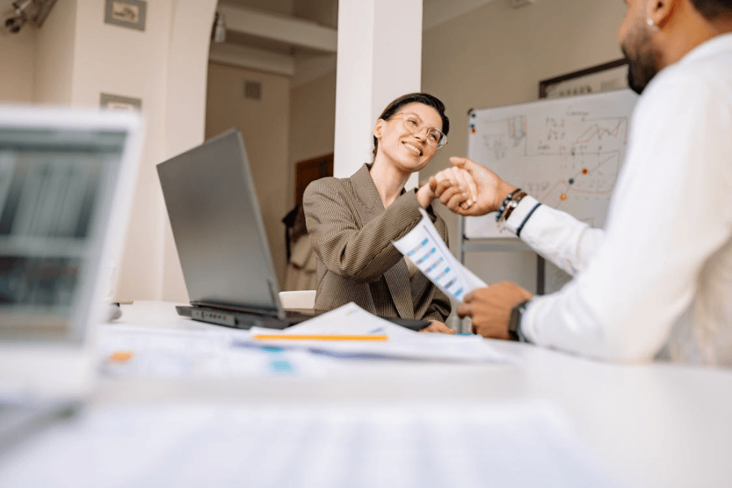 Professional woman over 40 confidently shaking hands after presenting her achievements during a salary discussion.