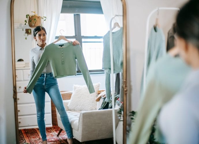 Woman over 40 choosing clothes at home as part of rebuilding personal style, confidence, and self-respect.
